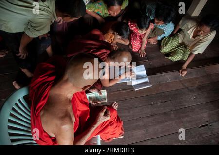 Le moine bouddhiste donner de l'argent aux personnes touchées par le cyclone dans un monastère de Kyauktan canton de Yangon Myanmar, Birmanie 15 Mai 2008 Banque D'Images