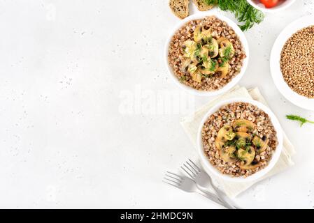 Porridge de sarrasin aux champignons rôtis dans un bol blanc sur fond de pierre avec espace de texte libre. Cuisine russe traditionnelle. Vue de dessus, plan d'appartement Banque D'Images