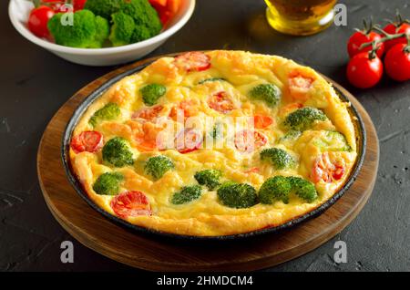 Frittata au brocoli et aux tomates sur fond de pierre sombre Banque D'Images