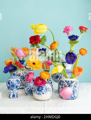 Une végétation luxuriante et naturelle agrémentée d'un vieux vase bleu Delft avec fleurs multicolores sur toile blanche sur fond bleu Banque D'Images