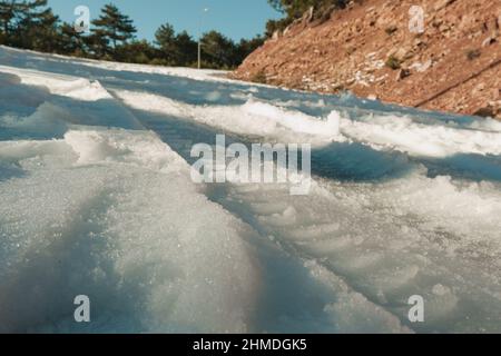 Piste de pneus et quelques empreintes de pas sur la neige en hiver. Banque D'Images