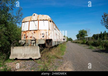 Le vieux train abandonné est resté debout pendant des années devant un bloc de béton Banque D'Images