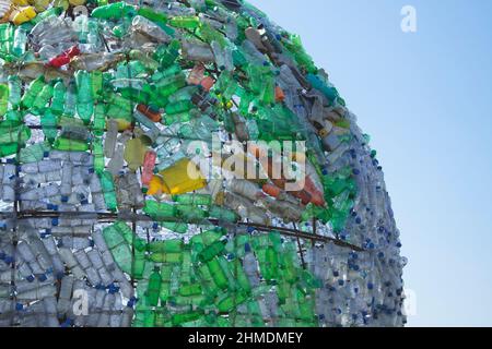 Partie colorée du globe faite d'ordures, de déchets en plastique et de bouteilles jetables en plastique, avec un ciel bleu comme fond Banque D'Images