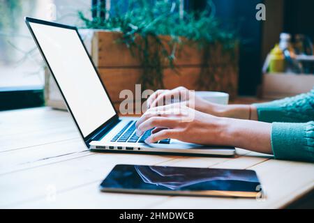 Femme sans visage tapant sur un ordinateur portable moderne situé sur une table avec une tablette Banque D'Images