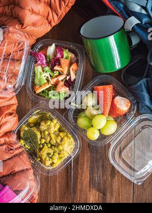 Repas préparés à la maison et emballés dans des boîtes à emporter : salade de tomates, fruits, fraises et raisins, viande en sauce aux pois. Préparation d'un Banque D'Images