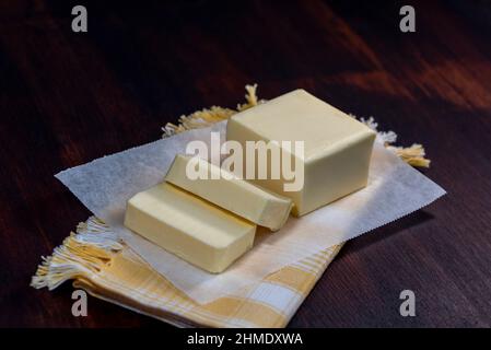 Pat de beurre de ferme avec des pailles avec une boule de beurre sur le dessus (vue de dessus sur une table en bois rustique format carré Banque D'Images