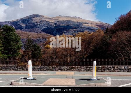 La cicatrice grise exposée de marches géantes en chute libre et de bâtiments restants d'une mine d'ardoise désuétude mar les pentes enneigées d'une montagne accidentée Banque D'Images