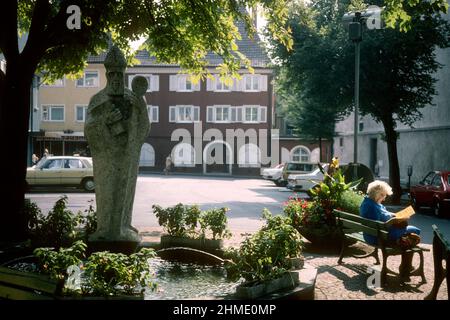 Femme âgée lisant sur le banc à côté de la statue de l'évêque Radolf de Vérone en 1981, Radolfzell, Bade-Wurtemberg, Allemagne Banque D'Images