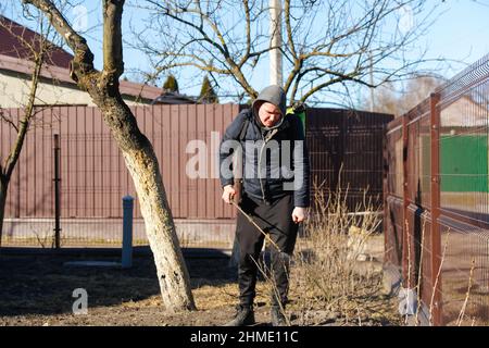 Agriculture écologique biologique.Défoquer l'homme fermier pulvérisant l'arbre avec un pulvérisateur manuel de pesticides contre les insectes dans le jardin de printemps.Agriculture et garde Banque D'Images