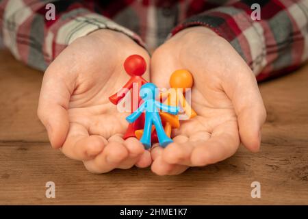 Figurines de la jeune famille dans les mains humaines. Concept de valeurs familiales, continuation et assurance. Prendre soin des enfants photo de fond Banque D'Images