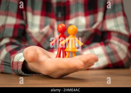 Figurines de la jeune famille dans la main humaine. Concept de valeurs familiales, continuation et photo de fond d'assurance Banque D'Images