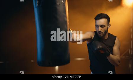 Entraînement sportif avec sac de punch sur fond sombre Banque D'Images