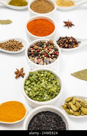 Condiments multicolores, différentes sortes d'épices dans des bols en céramique et des cuillères isolées sur blanc Banque D'Images