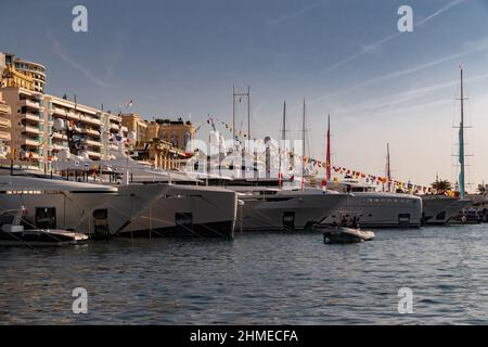 Beaucoup de yachts énormes sont dans le port de Monaco au lever du soleil, Monte Carlo, la montagne est en arrière-plan, panneau brillant du bateau à moteur, les megayachts sont amarrés Banque D'Images