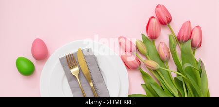 Réglage de la table de Pâques. Décoration pastel aux œufs et fleur de tulipe rose sur fond rose, vue d'en haut. Fête du printemps. Banque D'Images