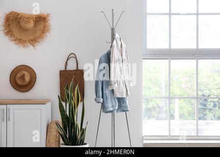 Porte-vêtements pour femmes, accessoires et maison près du mur lumineux Banque D'Images