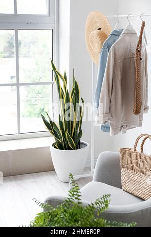 Porte-vêtements pour femmes, chapeau et maison près de la grande fenêtre Banque D'Images