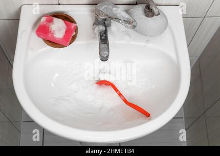 Lavabo en céramique avec éponge, savon et brosse dans la salle de bains Banque D'Images