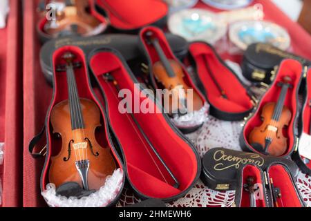 Petits violons miniatures avec leur bâton et leur étui rouge. Banque D'Images