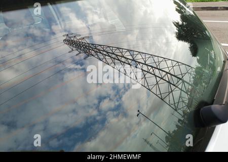 Câbles électriques de montant et haute tension reflétés dans la lunette arrière d'une voiture. Banque D'Images