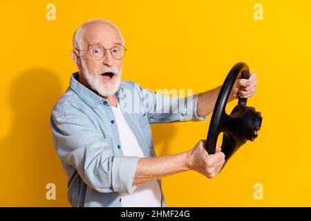 Portrait de profil de vue latérale d'un beau gris émerveillé homme tenir le volant étude apprendre isolé sur fond jaune vif Banque D'Images