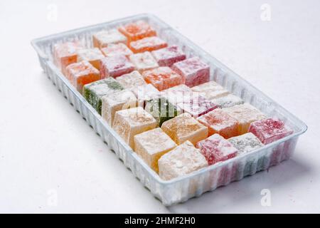 Délicieux lukum coloré, délice turc avec sucre en poudre sur fond blanc. Délicieuse délicatesse naturelle, dessert Banque D'Images