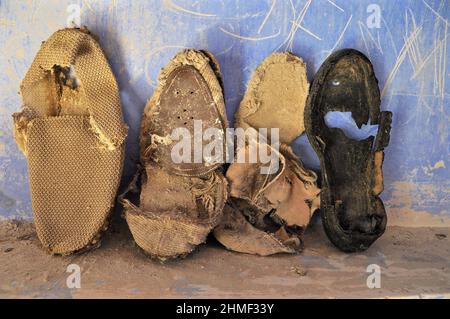 Rickety, chaussures décalées contre le mur bleu, chaussures pourries sur le sol, chaussure pourrie, épave de chaussure, kicker pourri, chaussure usée, patin usé Banque D'Images