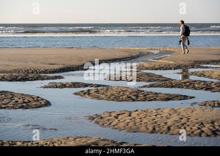 Un marcheur sur la plage à marée basse avec des bassins de marée, île de Juist, Basse-Saxe Mer des Wadden, Mer du Nord, Frise orientale, Basse-Saxe, Allemagne Banque D'Images