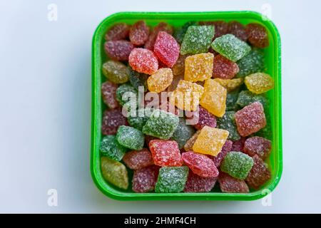 Sucettes multicolores de Montpensier dans une boîte sur fond blanc, sucreries sucrées, cadeaux, friandises, sucettes dans une boîte carrée. Banque D'Images