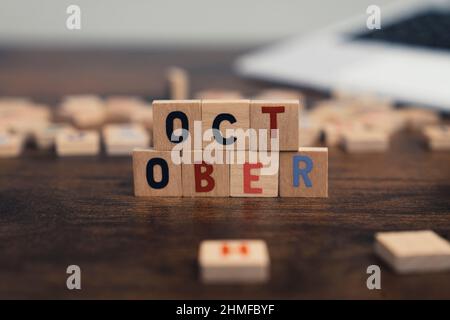 Le nom du mois d'octobre écrit sur des cubes en bois du plan d'examen du bureau d'ordinateur. Photo de haute qualité Banque D'Images