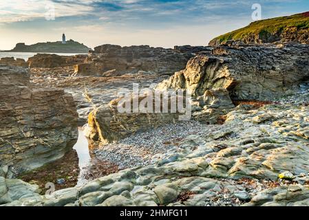 Mi-été chaud après-midi d'été, près du coucher du soleil, sous les falaises le long de la côte nord de Cornouailles, spectaculaires formations de granit et d'ardoise et phare Banque D'Images