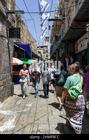 Les drapeaux israéliens survolent les touristes qui marchent dans la rue El Wad, ou la rue Haggai, dans le quartier musulman de la vieille ville de Jérusalem, en Israël. Banque D'Images