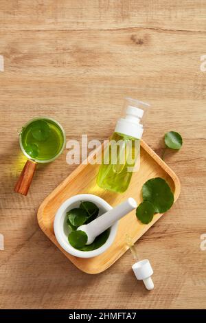 Extrait de Centella asiatica et modèle de pot cosmétique en planche à découper en bois et un fond en bois marron pour la publicité centella asiatica , top vie Banque D'Images