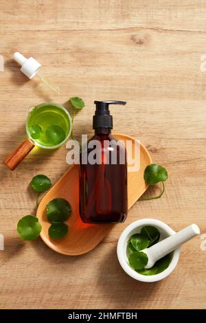 Extrait de Centella asiatica et modèle de pot cosmétique en planche à découper en bois et un fond en bois marron pour la publicité centella asiatica , top vie Banque D'Images
