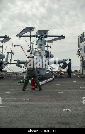 MER DES PHILIPPINES (janv 23, 2022) des Marines américaines affectées à l'escadron marin de Tiltrotor moyen (VMM) 165 (renforcé), 11th Marine Expeditionary Unit (MEU), effectuent des contrôles d'opérations de routine sur un Viper AH-1Z attaché à VMM-165 (rein.) à bord du navire d'assaut amphibie USS Essex (LHD 2), le 23 janvier 2022. Essex, le navire amiral du Essex Amphiobie Ready Group, ainsi que le MEU 11th, opère dans la zone d'exploitation de la flotte US 7th afin d'améliorer l'interopérabilité avec les alliances et les partenaires et de servir de force d'intervention prête à l'emploi pour assurer la sécurité maritime et une région Indo-Pacifique libre et ouverte. (É.-U. Mari Banque D'Images