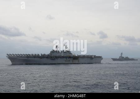 MER DES PHILIPPINES (fév 7, 2022) le navire d'assaut amphibie de classe américaine USS America (LHA 6) et le destroyer à missile guidé de classe Arleigh Burke USS Dewey (DDG 105) naviguent en formation pendant l'exercice Noble Fusion. Des navires des groupes de prêts amphibies de l'Amérique et de l'Essex et du groupe de grève des transporteurs Abraham Lincoln, aux côtés de la Force d'autodéfense maritime du Japon, participent à l'exercice Noble Fusion. Noble Fusion souligne que les forces expéditionnaires navales déployées par la Marine et le corps des Marines peuvent rapidement regrouper en mer les équipes de l'unité expéditionnaire maritime/du groupe de préparation amphibie Banque D'Images