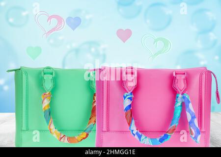 Modèle bonne Saint Valentin ou Fête des mères. Un beau sac à main vert et rose pour femmes décoré d'un tissu coloré sur la table au-dessus de bleu abstrait Banque D'Images