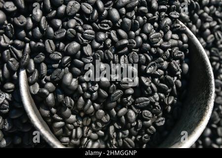 Grains de café robusta aromatiques fraîchement torréfiés dans une cuillère argentée sur des grains de café moulus. Café biologique. Produit local de Krabi, Thaïlande. Vue de dessus. Banque D'Images