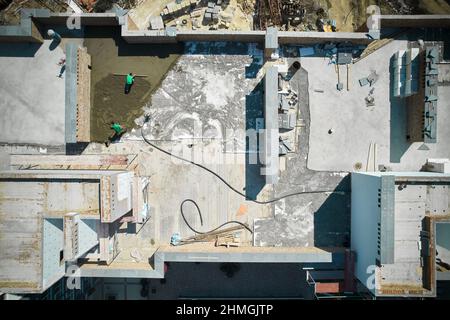 Vue aérienne du chantier de construction avec les ouvriers, les matériaux de construction, les murs de briques et le processus de table de plancher. Les entrepreneurs crient le sol sur le toit du bâtiment résidentiel. Banque D'Images