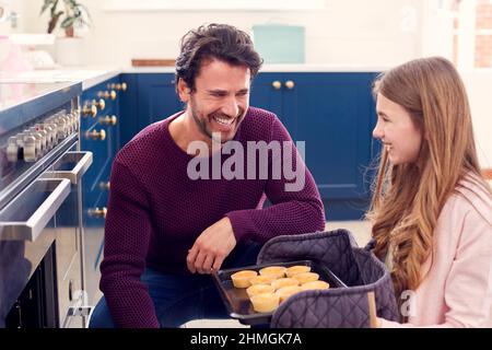 Père avec une fille adolescente prenant des cupcakes maison fraîchement sortis du four Banque D'Images