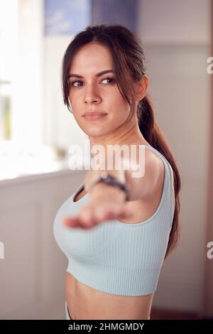 Femme faisant du yoga portant des vêtements de fitness et moniteur d'activité s'étirant dans la chambre à la maison Banque D'Images