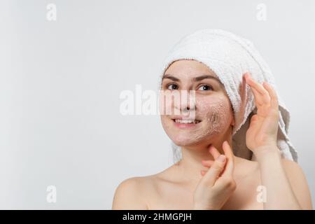 Une jeune femme souriante avec un masque naturel ou un ubtan sur son visage et une serviette blanche sur sa tête, un lieu de texte, un espace de copie Banque D'Images