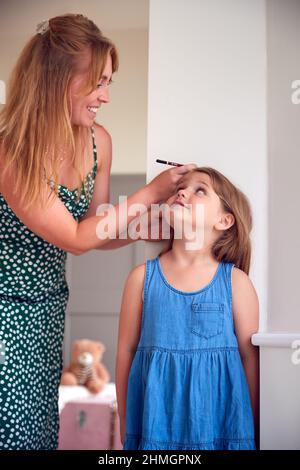 Mère mesurant la taille de la fille et marquant sur le mur à la maison Banque D'Images