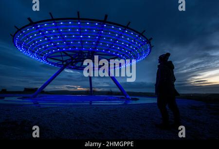 Haslingden, Lancashire, Royaume-Uni, mercredi 09 février 2022. Un marcheur s'arrête pour admirer le soleil couchant au panopticon de Halo au-dessus de la ville de Haslingden, Banque D'Images