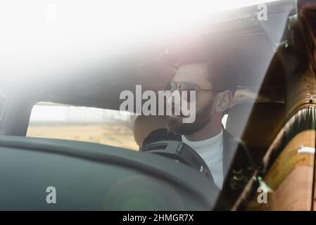 vue du pilote barbu dans des lunettes de soleil stylées à l'intérieur du cockpit à travers le pare-brise de l'hélicoptère Banque D'Images