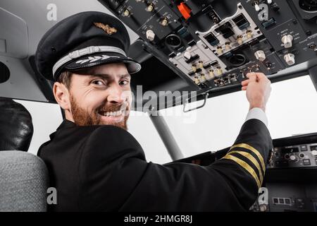 pilote gai dans le chapeau atteignant le panneau de pavillon avec un jeu de commutateurs dans le simulateur d'avion Banque D'Images