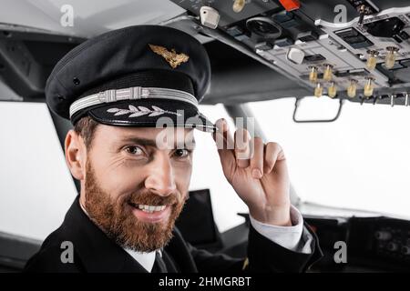 pilote gai en train de régler le capuchon et de regarder la caméra dans le simulateur d'avion Banque D'Images