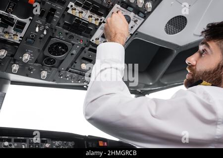 pilote barbu appuyant sur le bouton du panneau de pavillon dans le simulateur d'avion Banque D'Images