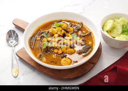 Curry de crevettes acidulé et épicé. De minuscules crevettes au curry à base de mangue séchée et d'épices indiennes, garnies de coriandre et servies avec des tranches de concombre. Banque D'Images