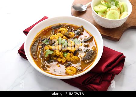 Curry de crevettes acidulé et épicé. De minuscules crevettes au curry à base de mangue séchée et d'épices indiennes, garnies de coriandre et servies avec des tranches de concombre. Banque D'Images